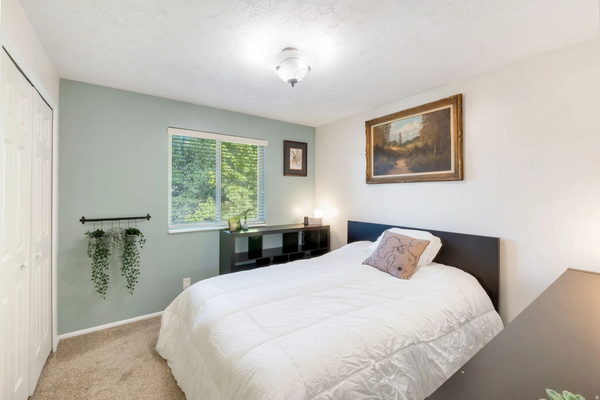 Carpeted interior room featuring a window with blinds, bi-fold closet doors, and an overhead light fixture