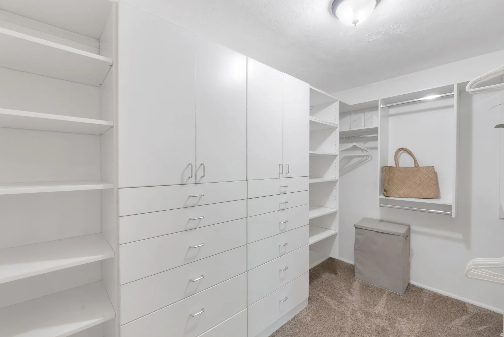 Custom closet system featuring extensive white cabinetry, multiple drawers with modern pulls, open shelving, and integrated hanging rods