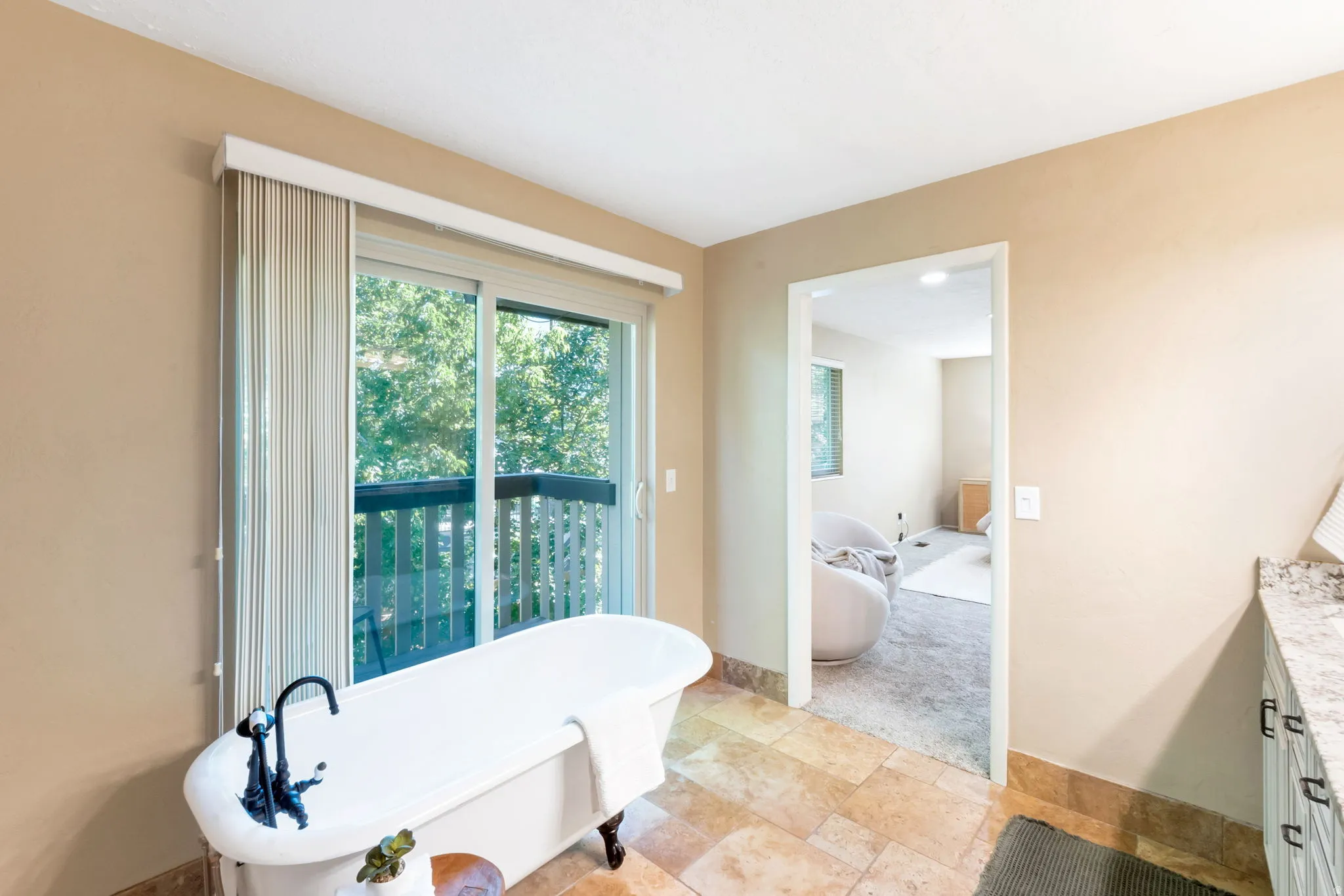 Freestanding clawfoot tub with a dark bronze faucet, complemented by a sliding glass door opening to a private balcony