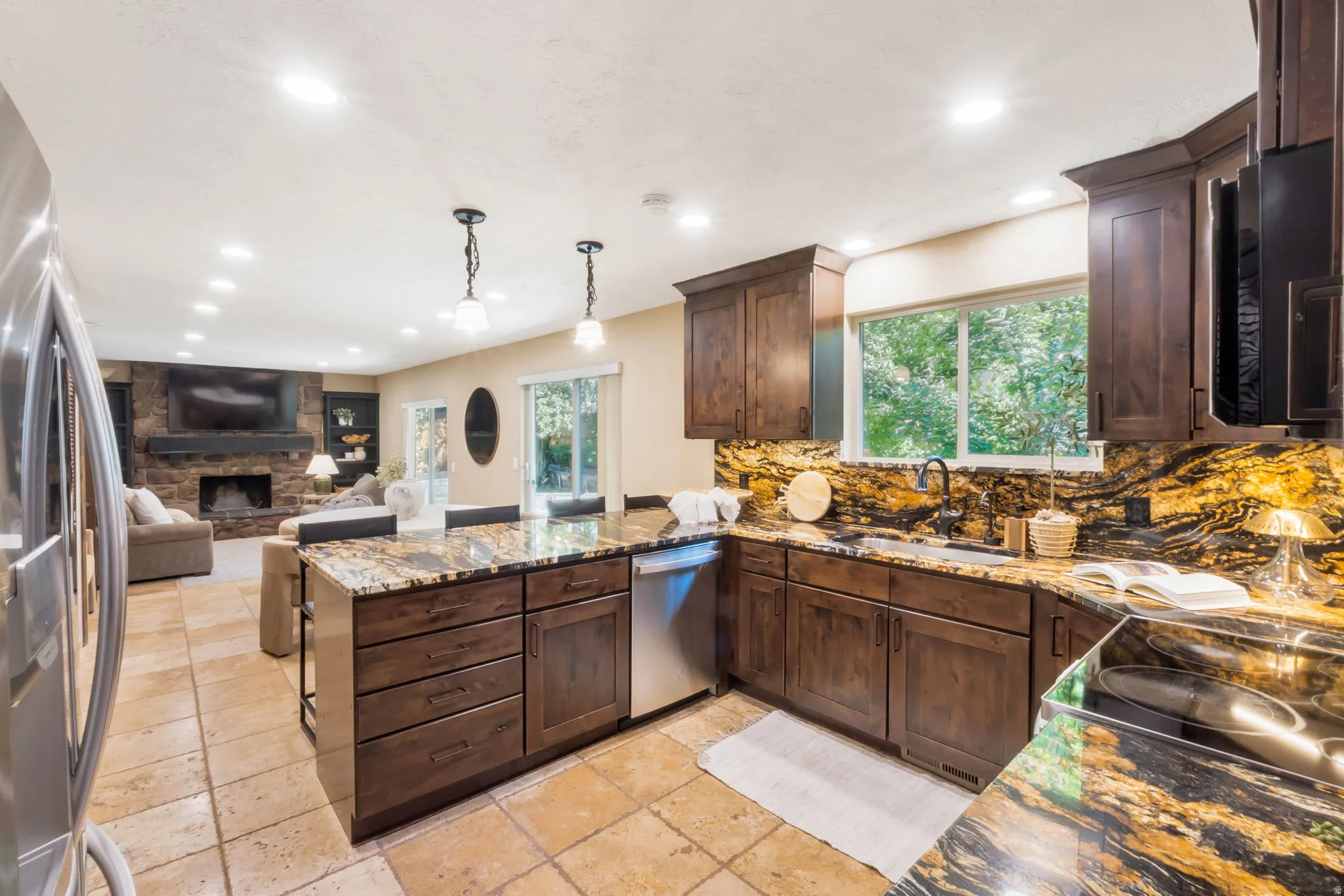 Expansive kitchen featuring wood cabinetry, granite countertops, tile flooring, and stainless steel appliances