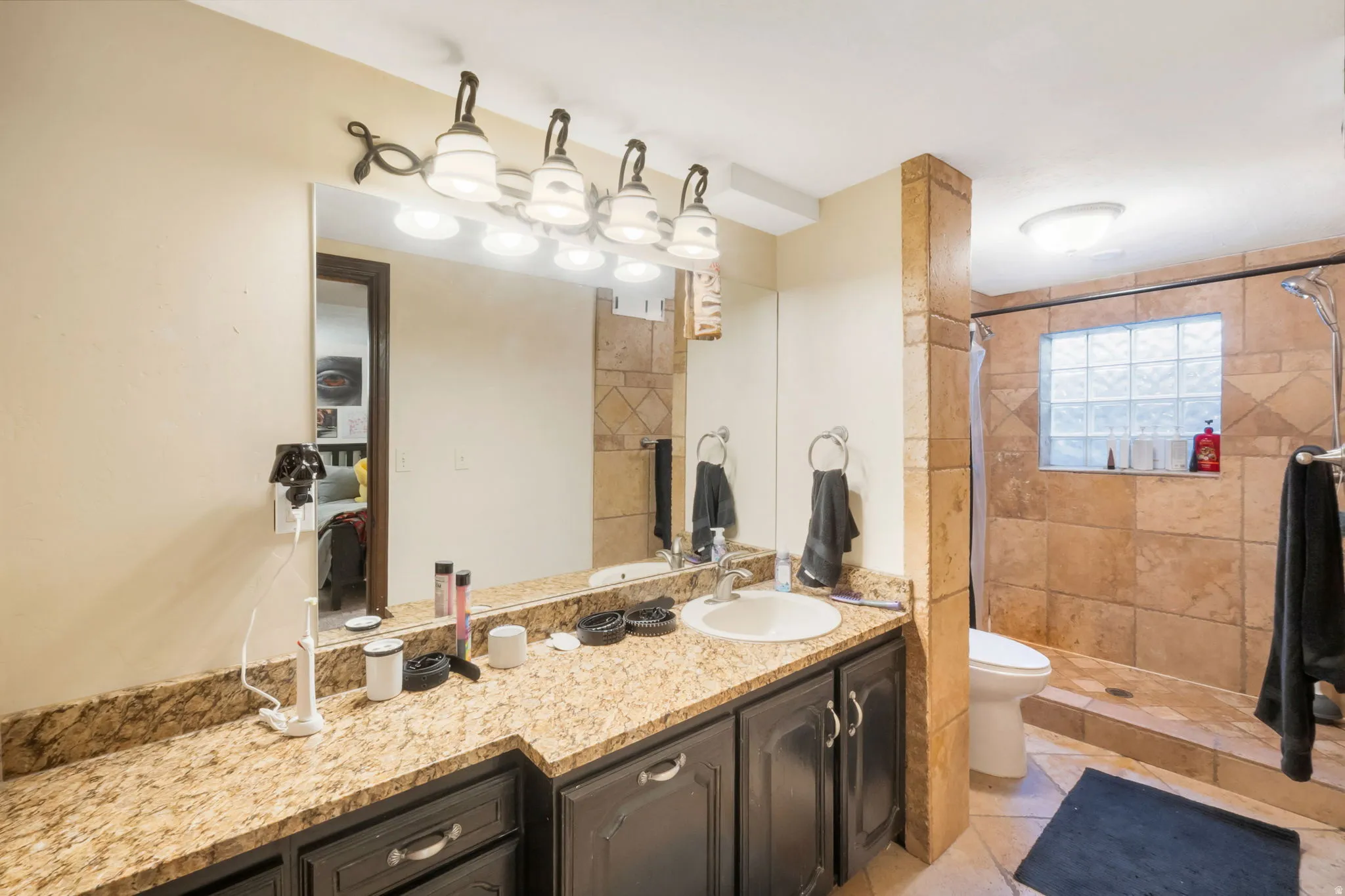 Bathroom featuring a spacious vanity with a speckled countertop, integrated sink, and dark wood-finish cabinetry