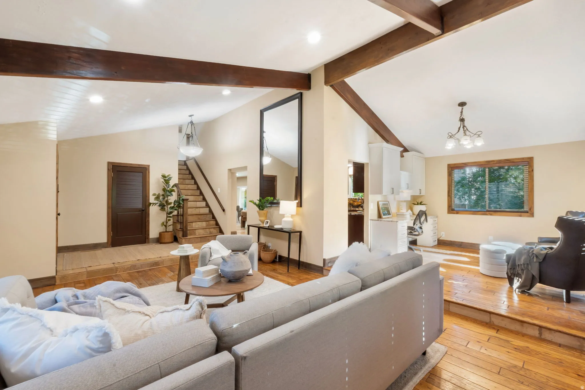 Spacious living area featuring wood-finish flooring, exposed ceiling beams, a vaulted ceiling, and recessed lighting