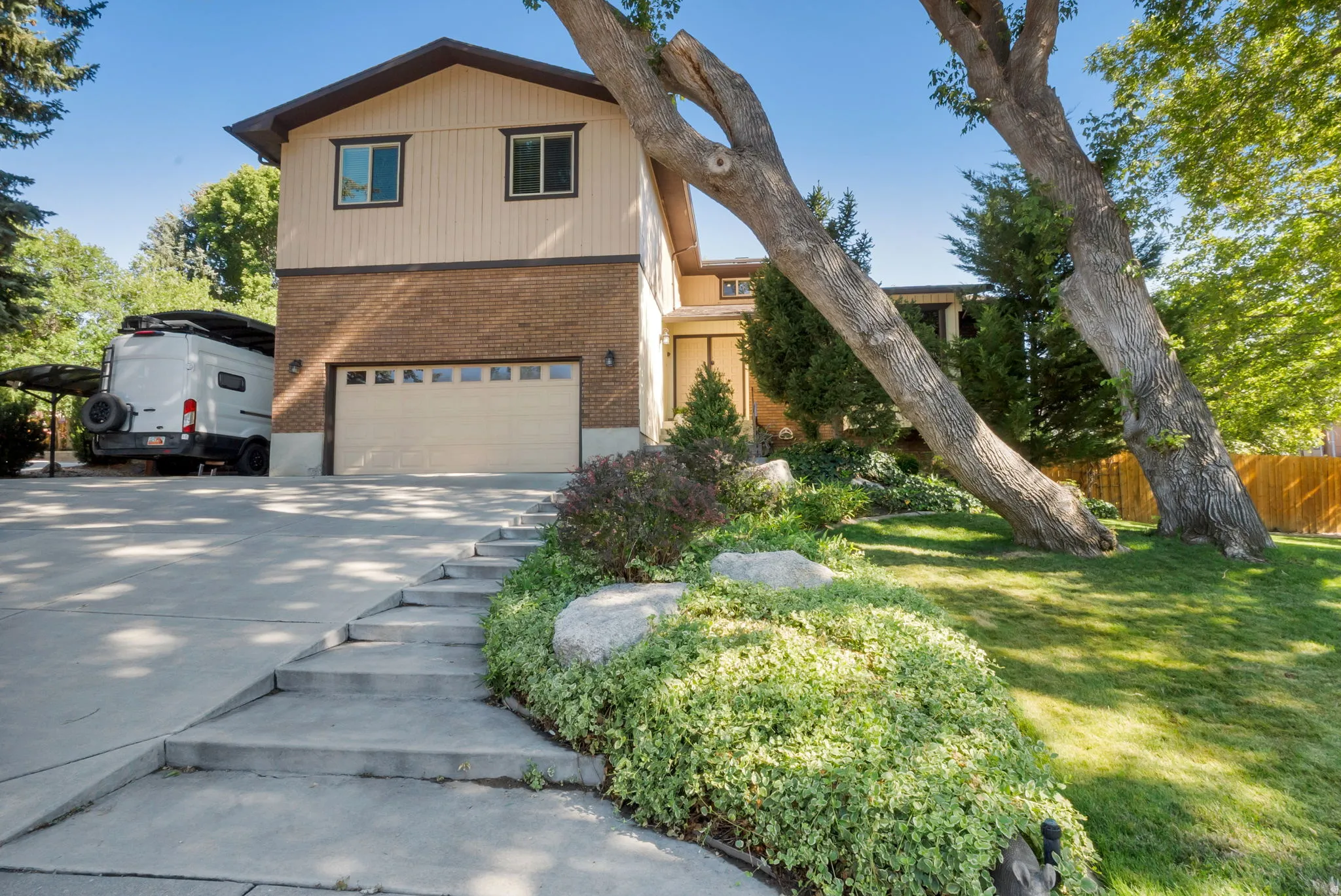 Split-level residence featuring brick and siding facade, an attached two-car garage, and a concrete driveway