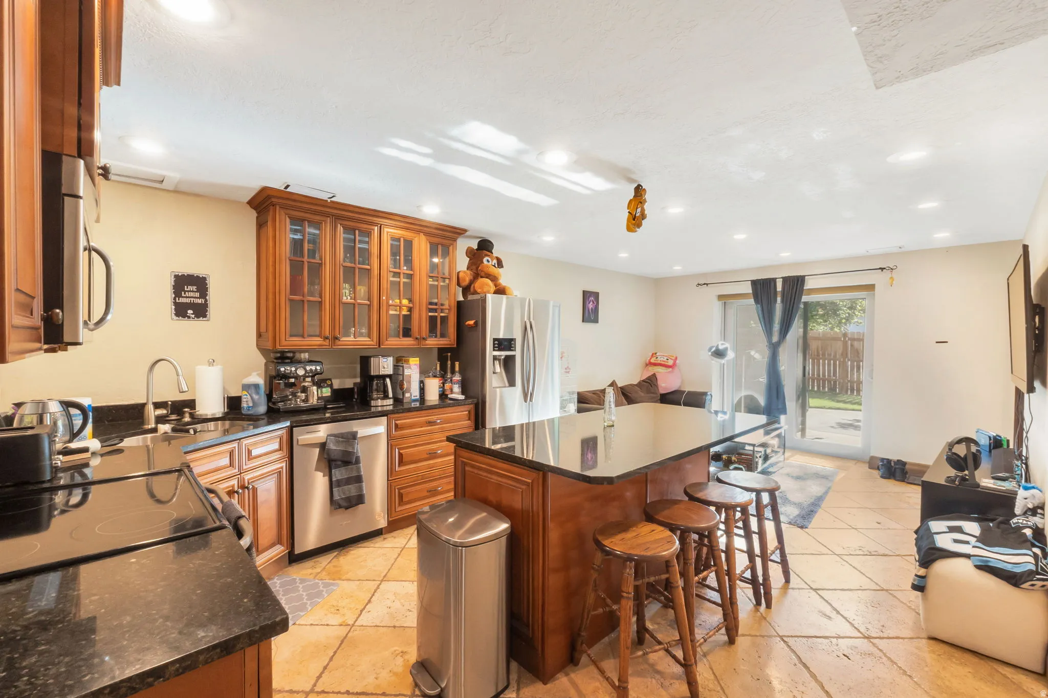 Kitchen with wood cabinetry, dark countertops, and stainless steel appliances
