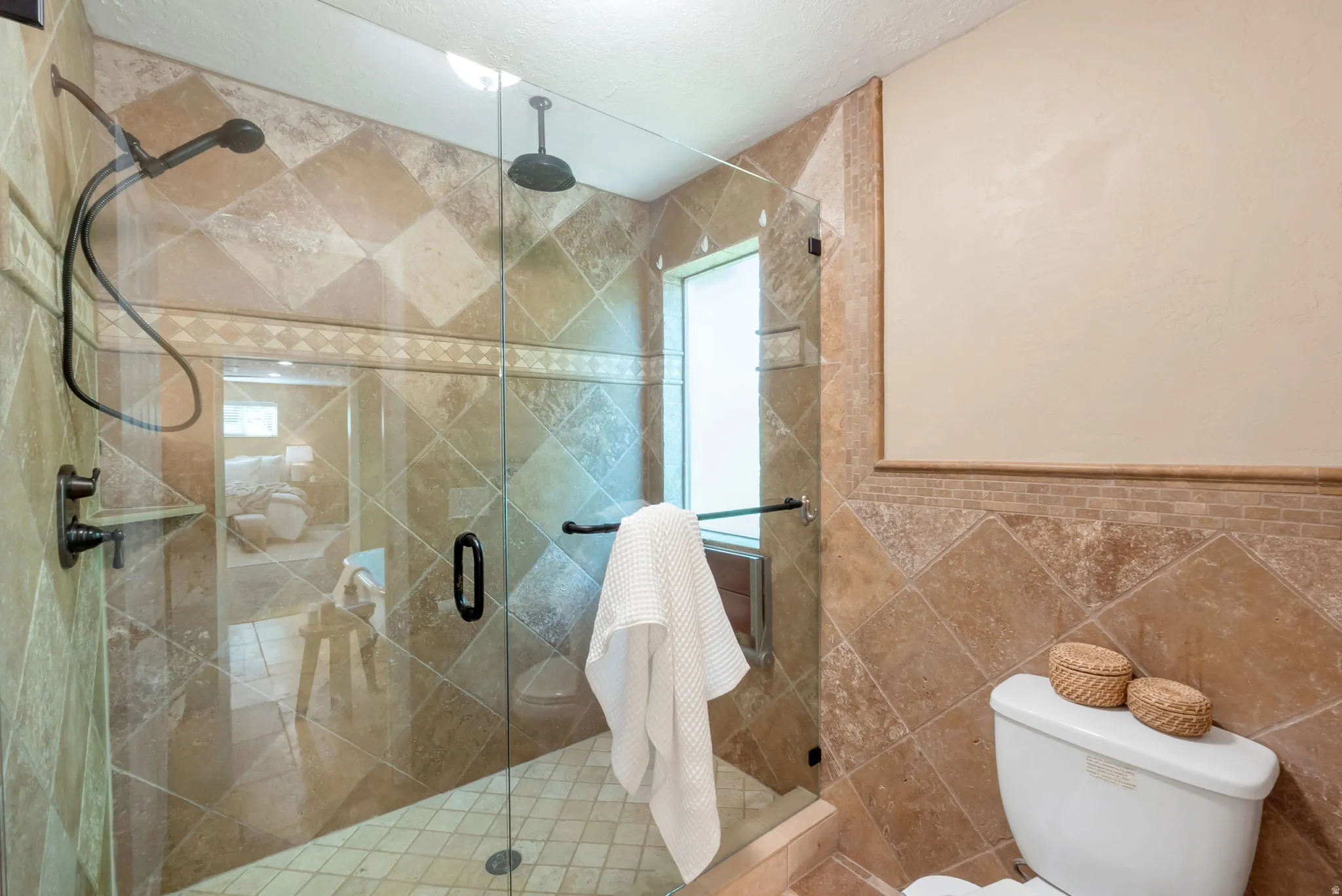 Enclosed shower with clear glass door, featuring a rain shower head and a handheld shower fixture