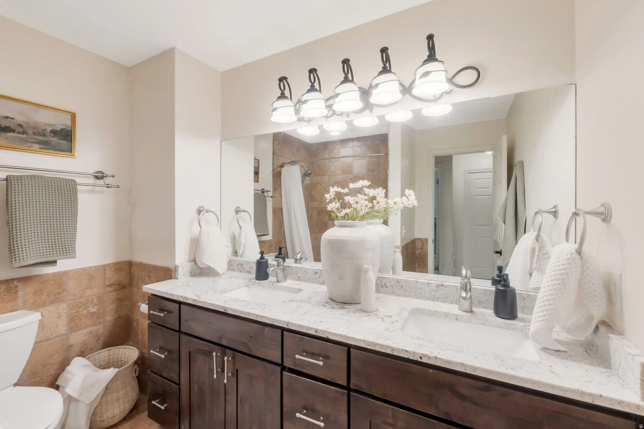 Bathroom featuring a dual vanity with dark wood cabinetry, light-colored stone countertops, and undermount sinks