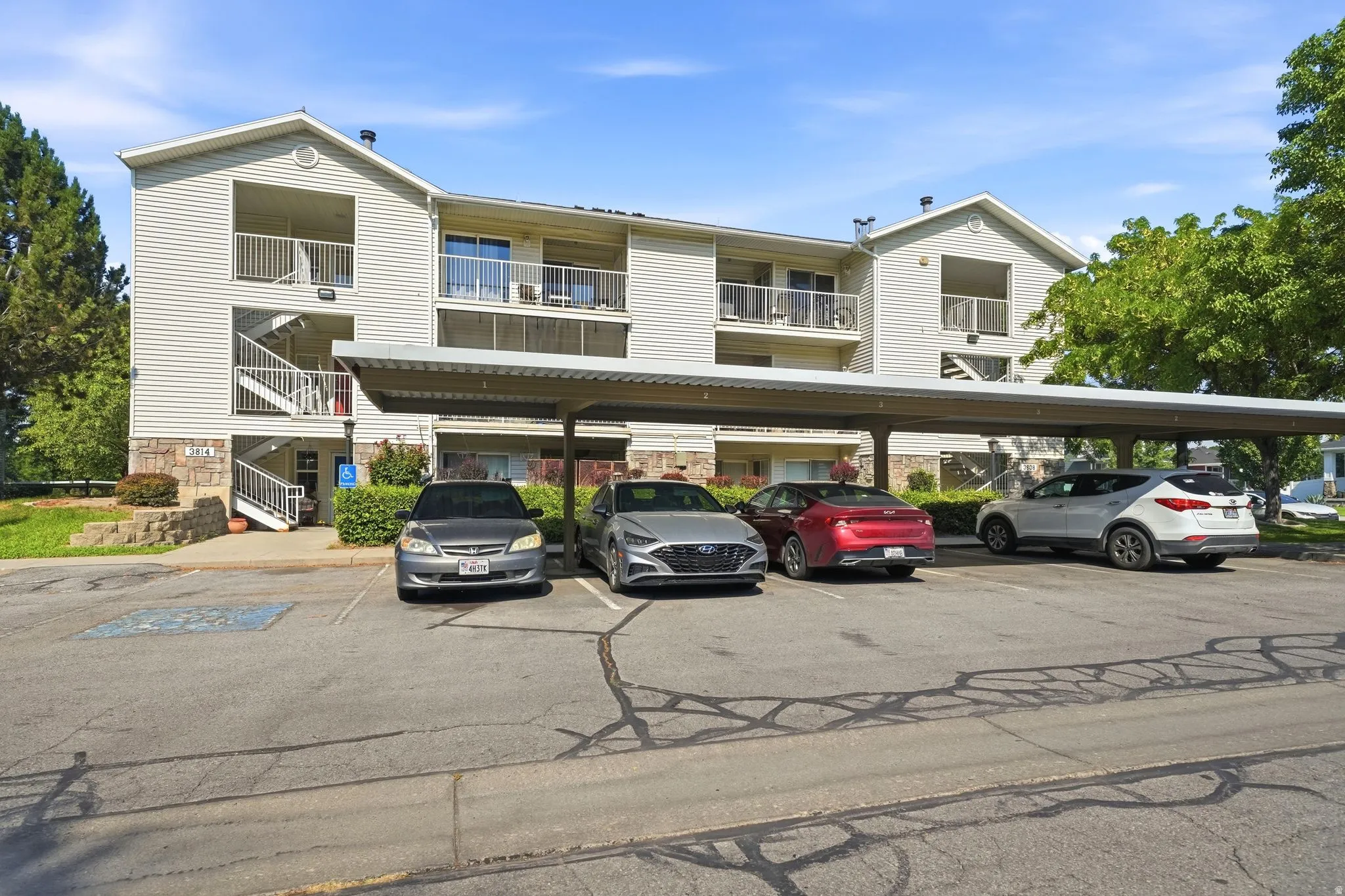 Multi-unit residential building featuring classic architectural design with horizontal siding exterior, pitched rooflines, and covered parking beneath
