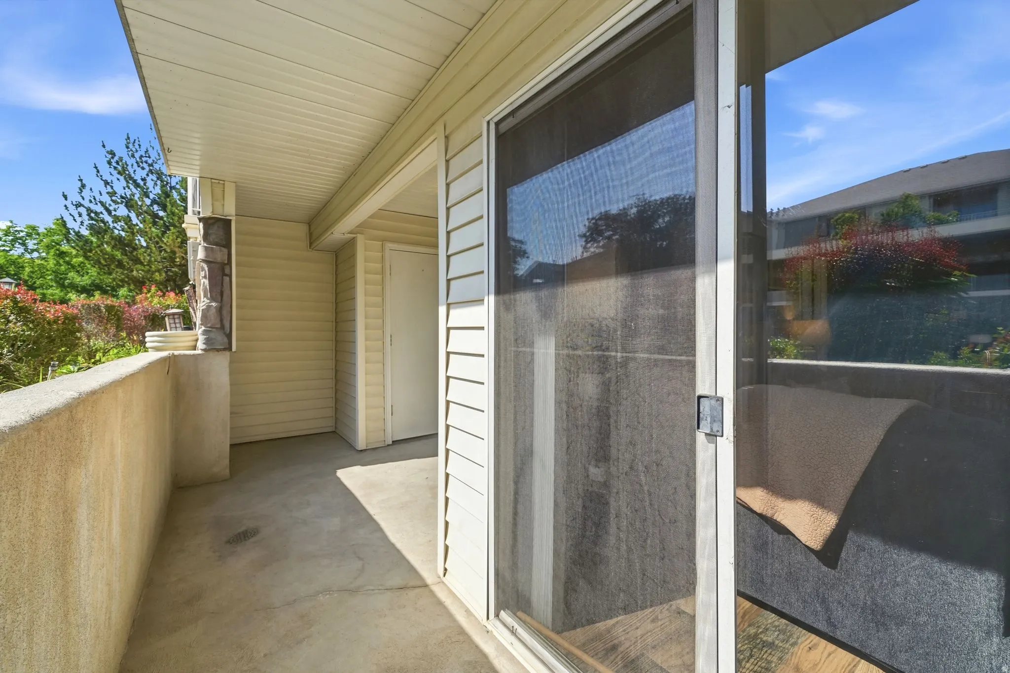 Covered patio with sliding glass door entry, concrete flooring, and white vinyl siding