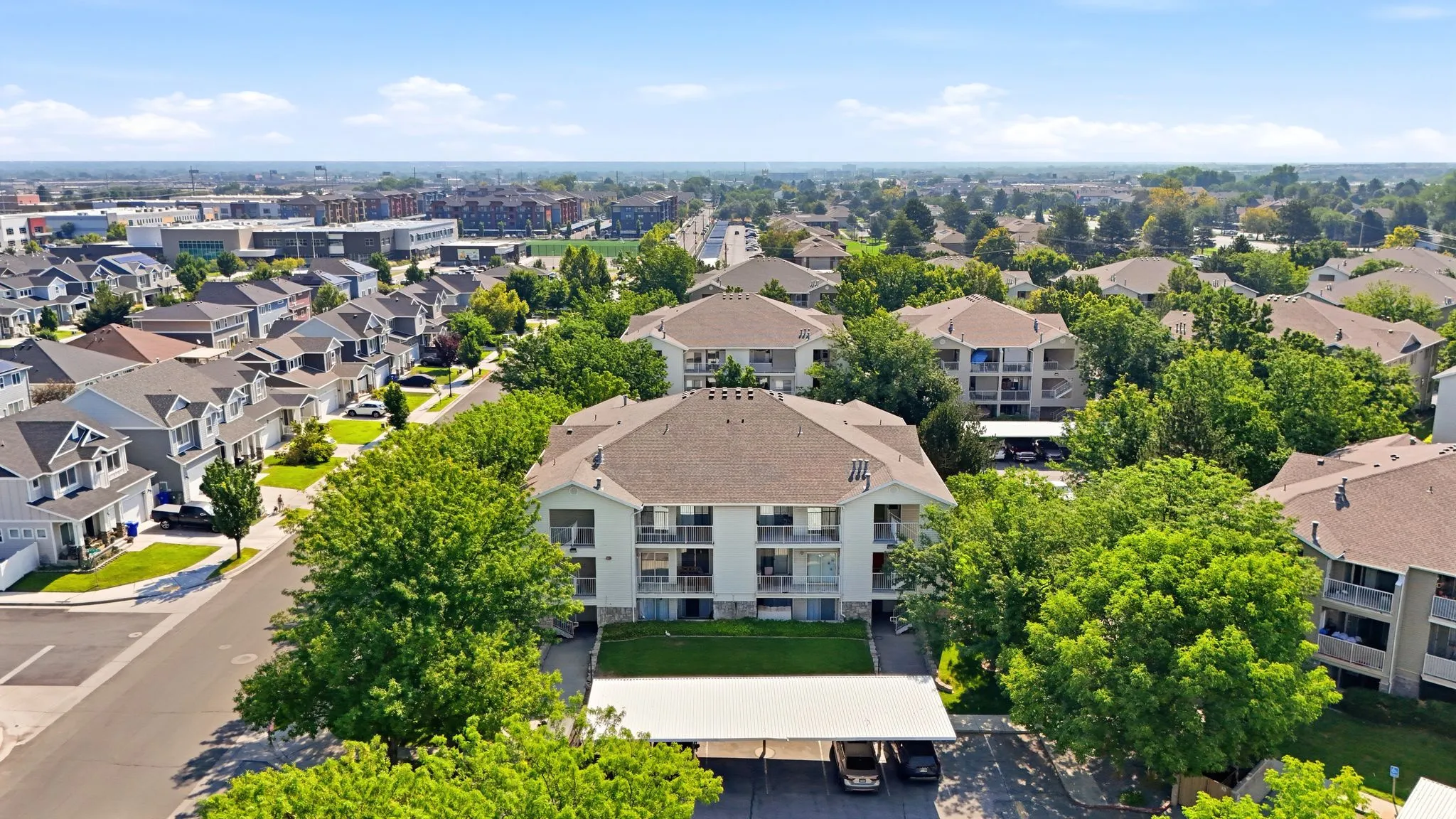 Striking residential community featuring a prominent multi-unit apartment building with a distinctive domed roof, manicured landscaping with mature trees, and professional hardscaping