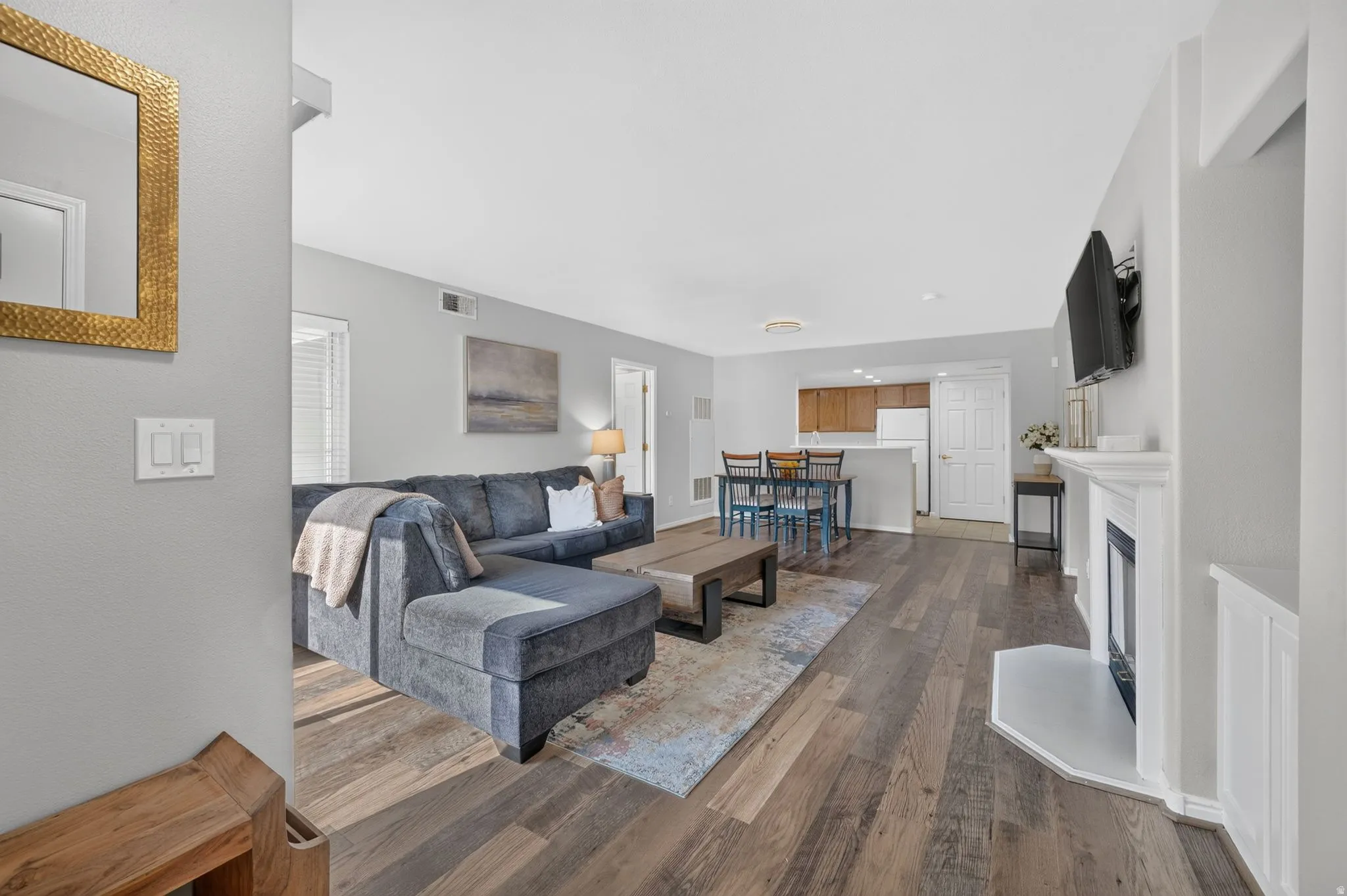 Open-concept living area featuring a sectional sofa, wood-finish flooring throughout, and abundant natural light from multiple windows