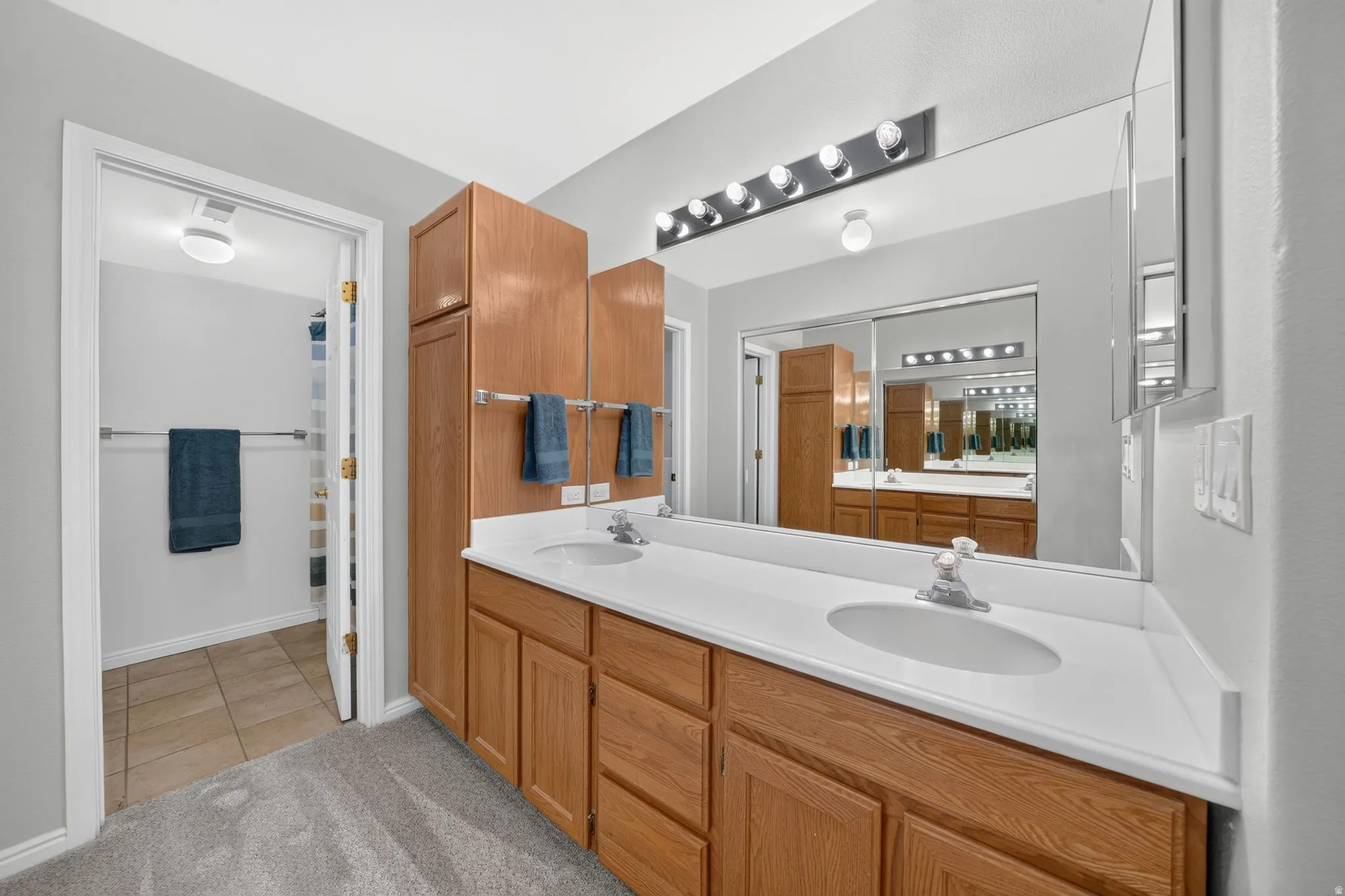 Master bathroom featuring dual vanities with white solid surface countertops, wood-finish cabinetry with ample storage, and polished chrome faucetry