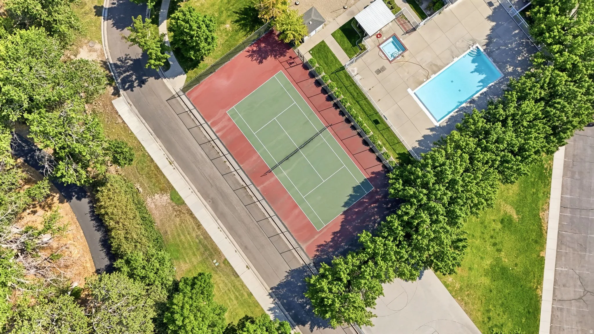 Professional recreational amenities featuring two well-appointed tennis courts with clay-style playing surfaces, complemented by a resort-style swimming pool