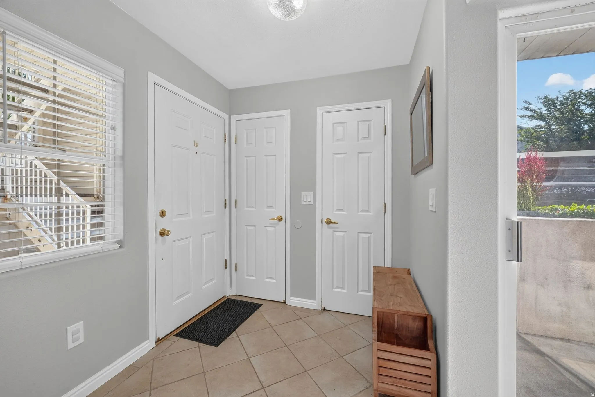 Welcoming foyer featuring neutral gray walls, ceramic tile flooring, and multiple six-panel white doors providing access to primary living spaces
