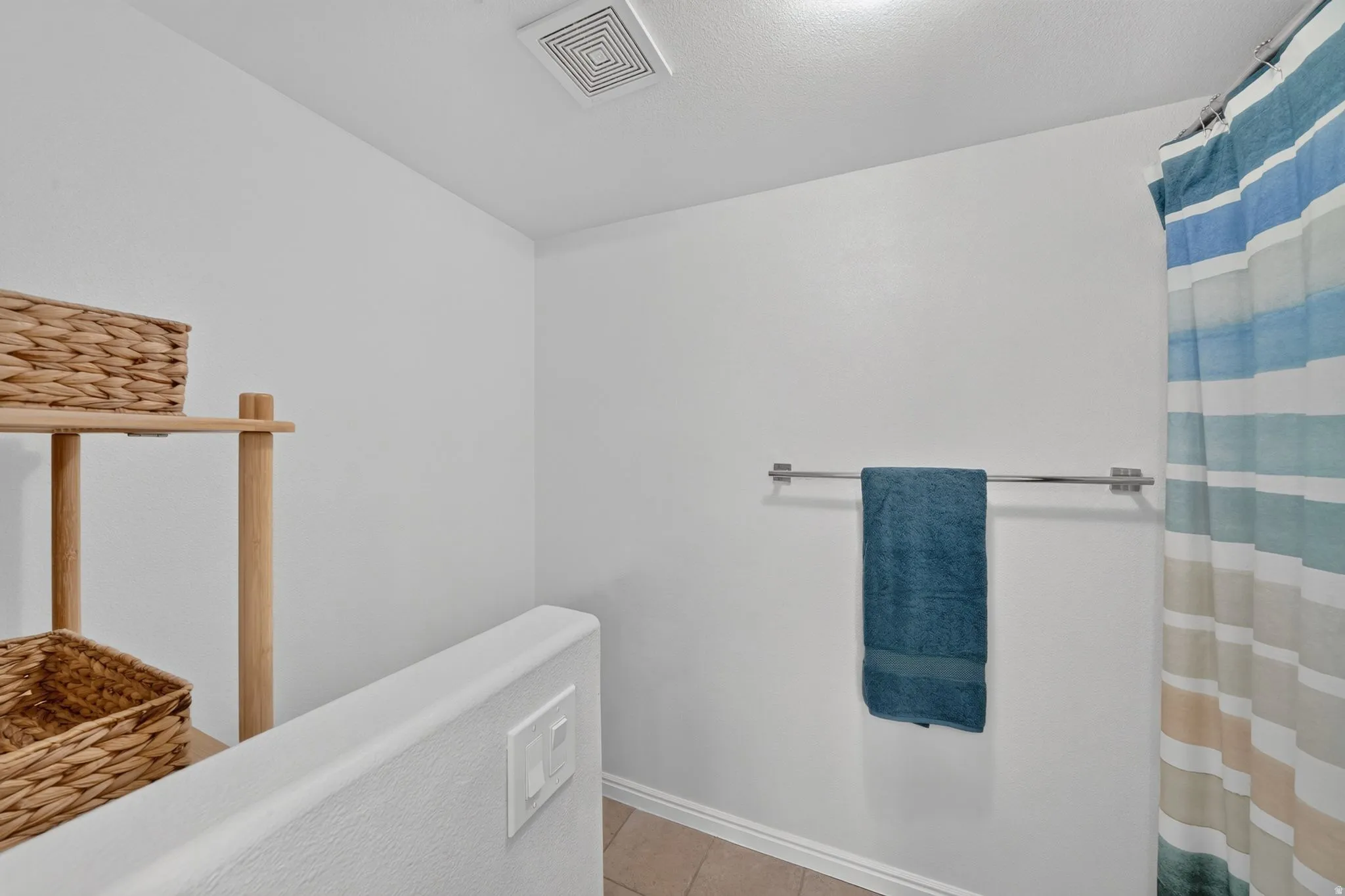 White wall finishes with a mounted towel bar and a shower curtain rod