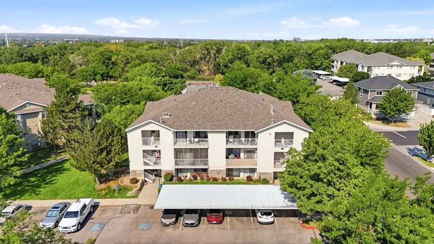 Multi-unit residential building featuring a clean white exterior with symmetrical architectural design, pitched roof with dimensional shingles, and multiple balconies with metal railings