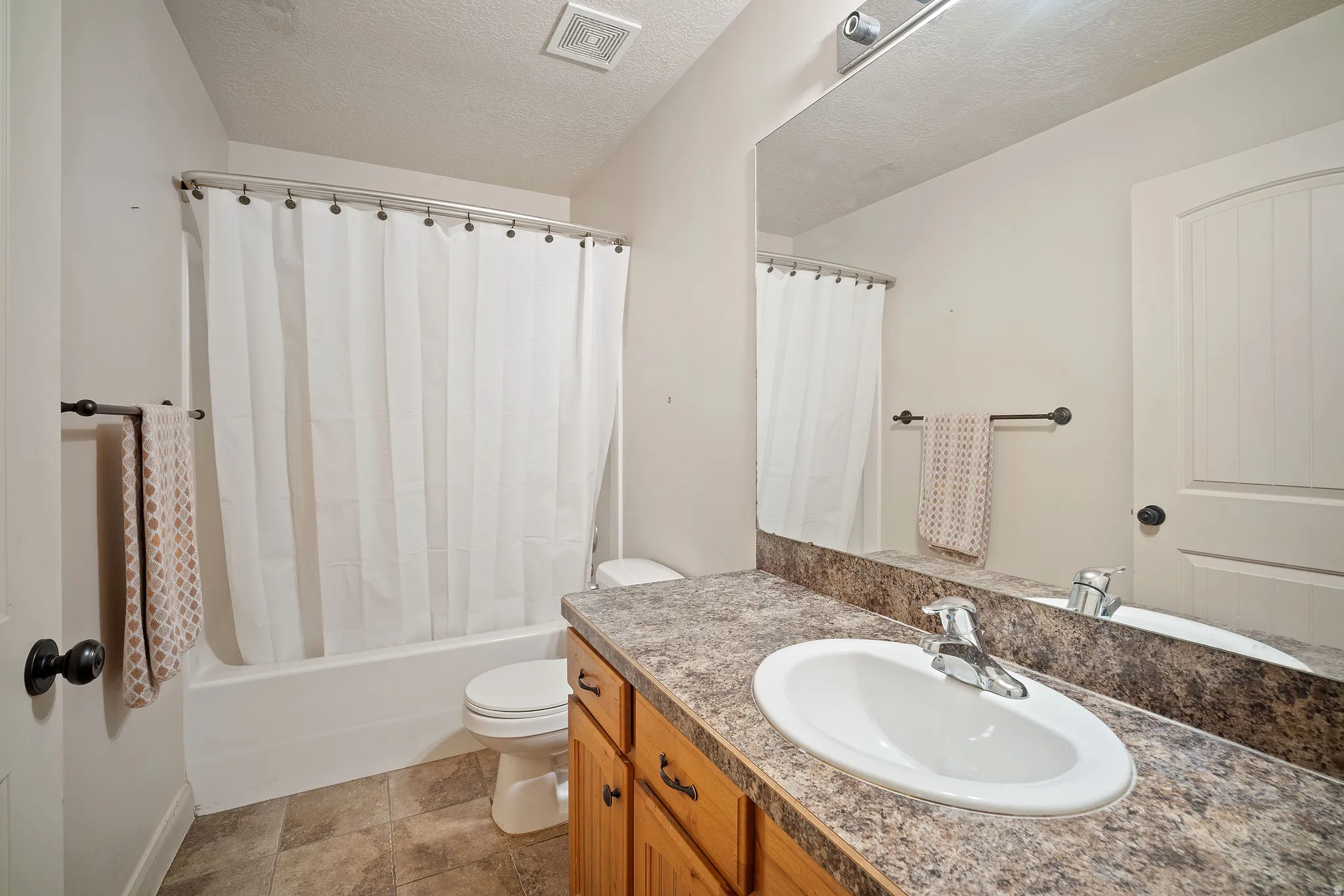 Bathroom featuring a built-in vanity with wood cabinetry, a laminate countertop, and an undermount sink with a chrome faucet