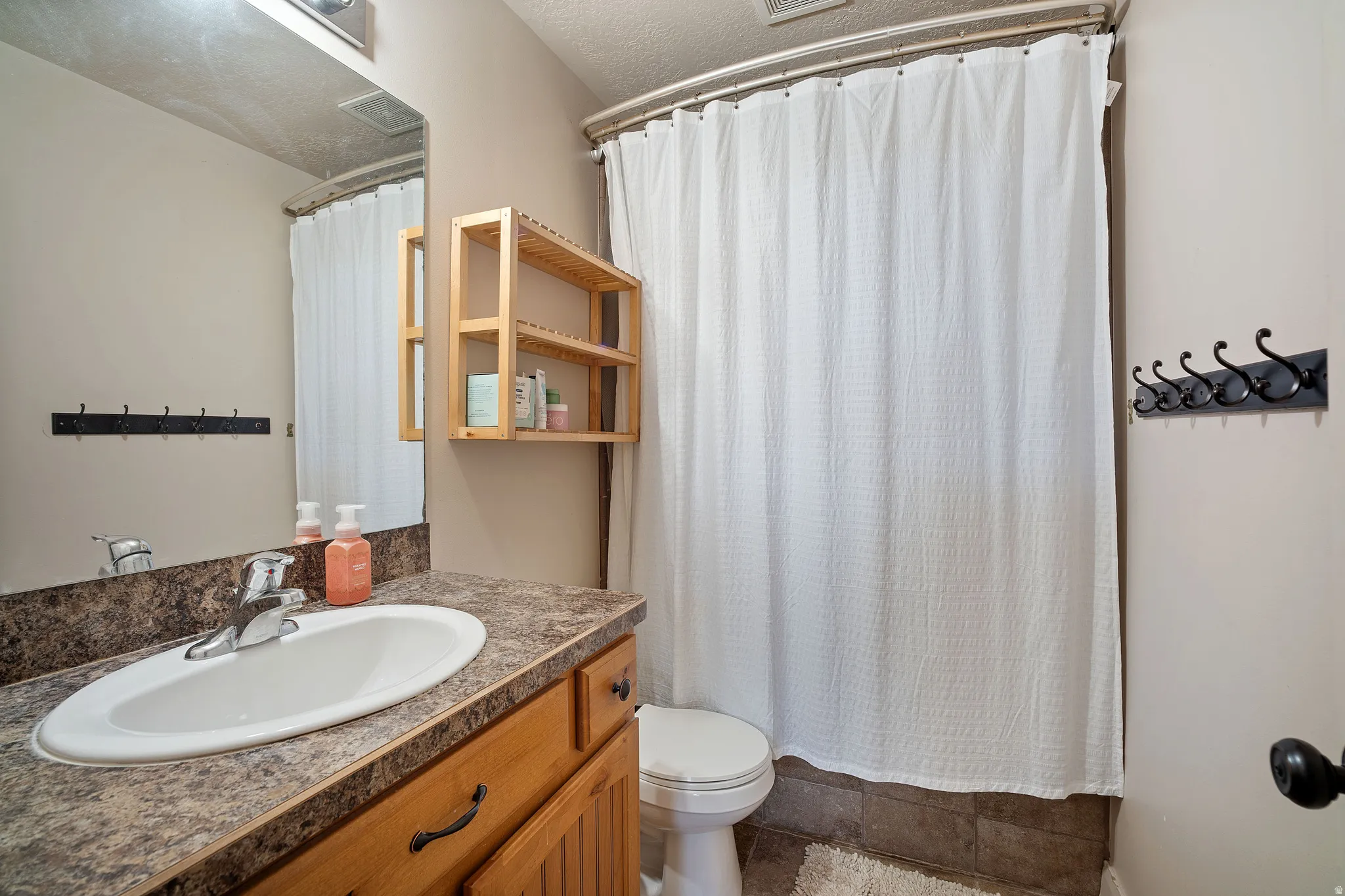 Bathroom featuring a wood-finish vanity with a laminate countertop, an undermount sink, and a framed mirror