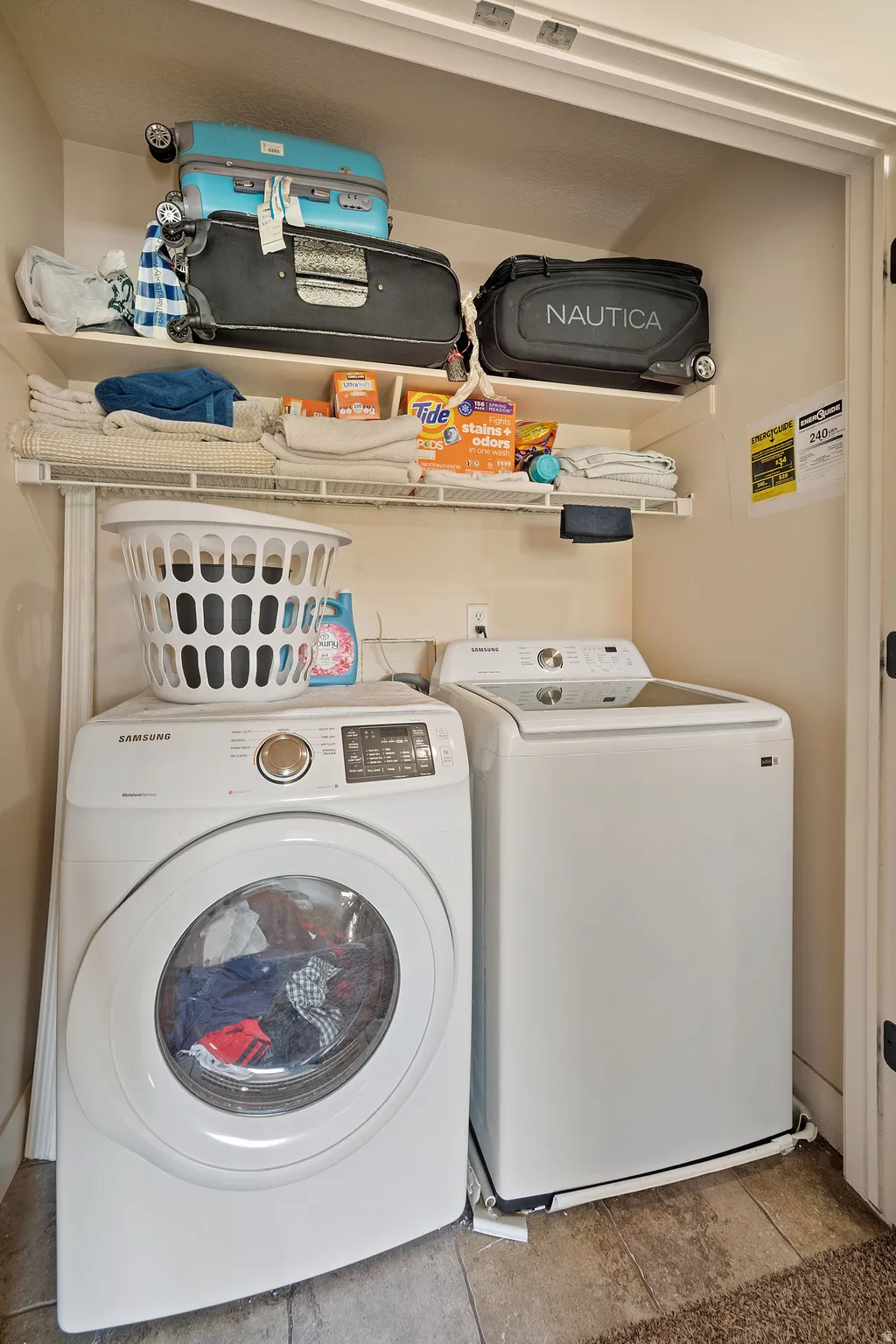 Dedicated laundry area featuring a white front-load washing machine and a white top-load dryer, with convenient overhead wire shelving