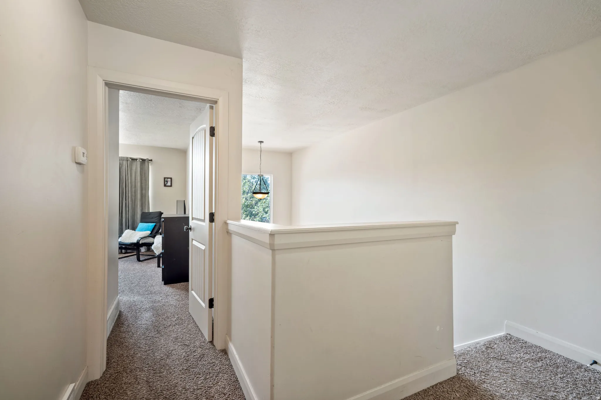 Carpeted hallway with painted walls and a textured ceiling