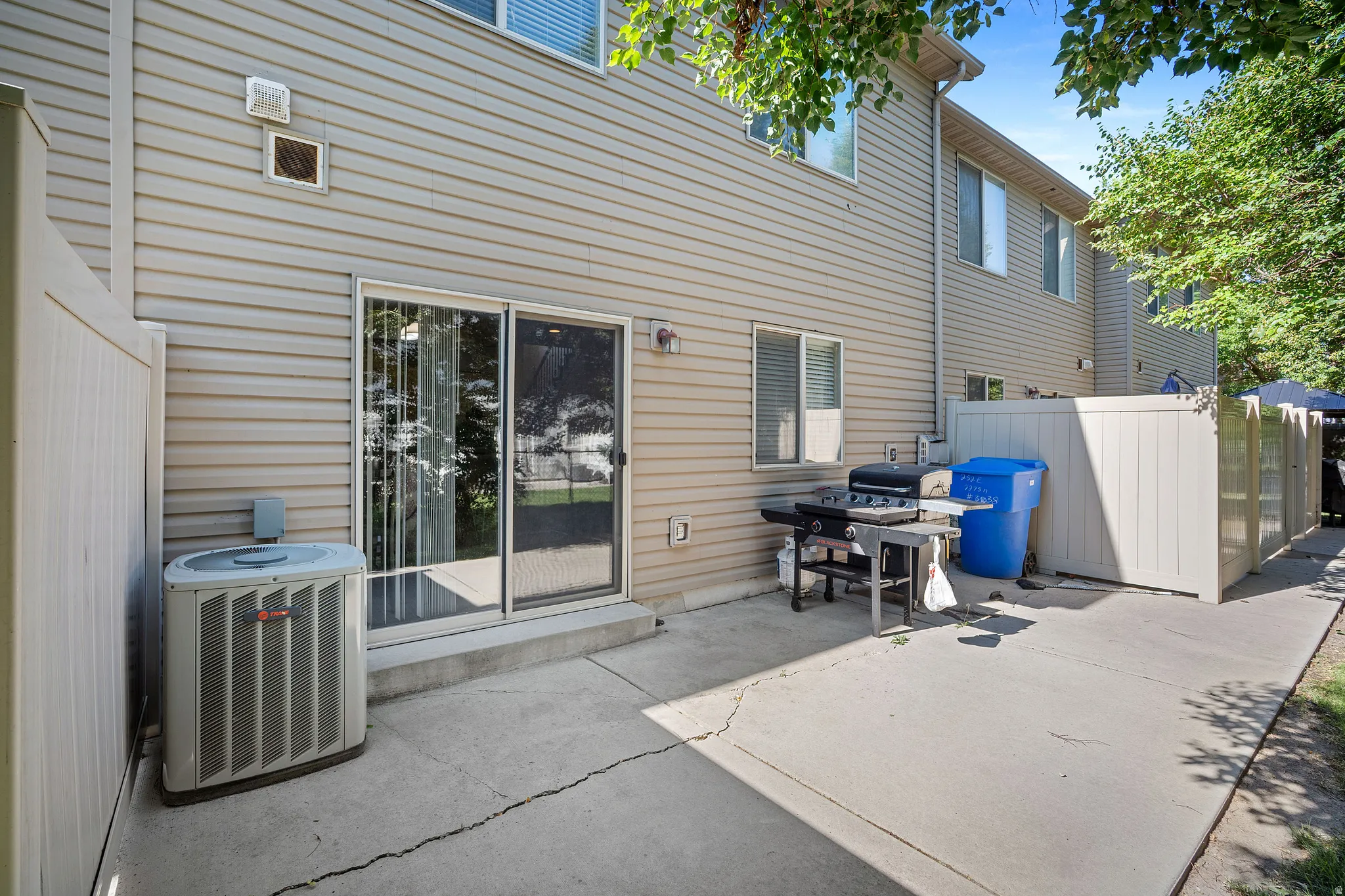 Rear exterior with beige siding, featuring a concrete patio