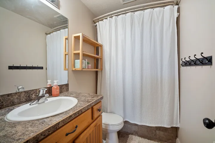 Bathroom featuring a wood-finish vanity with a laminate countertop, an undermount sink, and a framed mirror