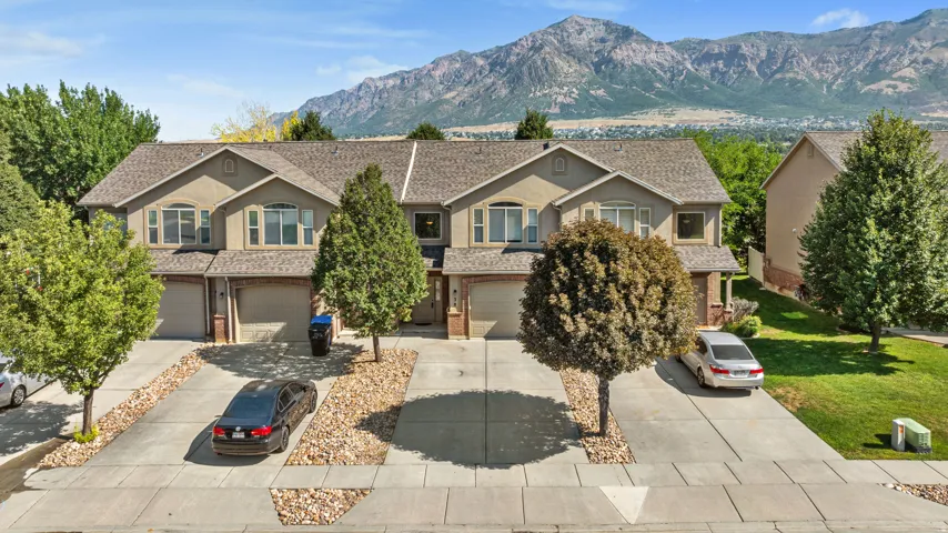 Tri-level townhouse exterior featuring stucco siding, multiple gabled rooflines, and attached garages