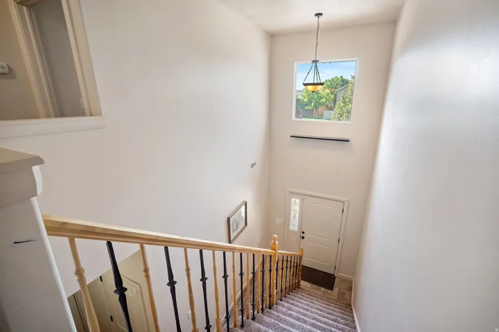 Two-story foyer with a tall window, pendant light fixture, and wood railing with black metal balusters