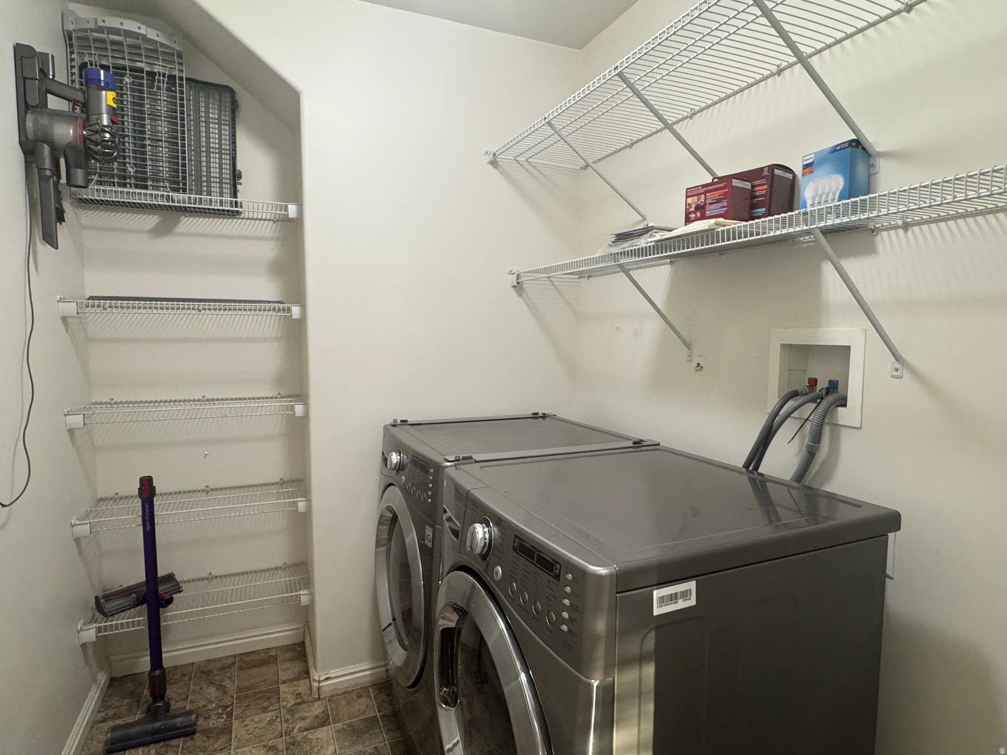 Dedicated laundry space featuring a stacked washer and dryer, convenient water hookups, and ample wire shelving