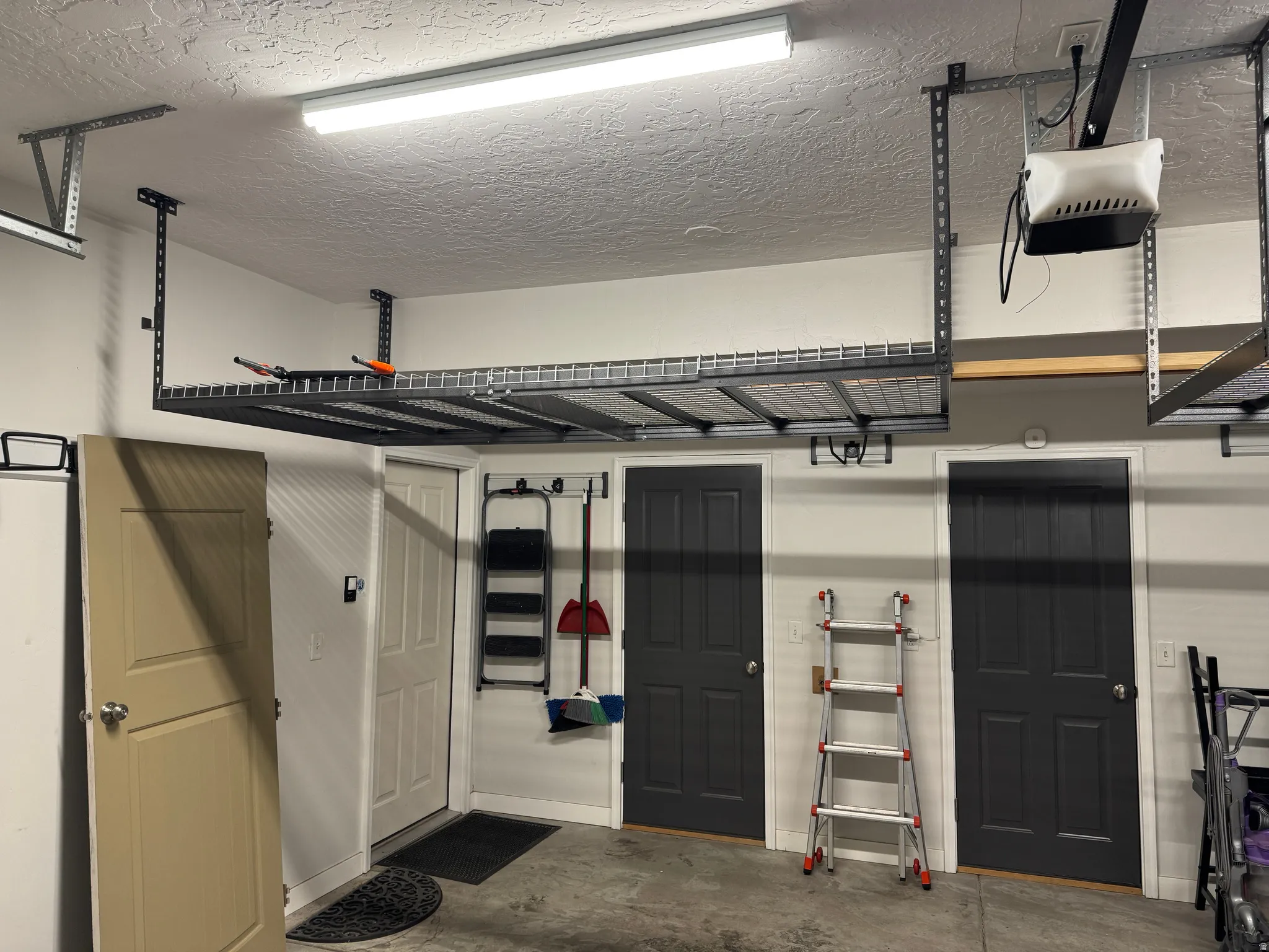 Garage interior featuring concrete flooring and overhead wire shelving
