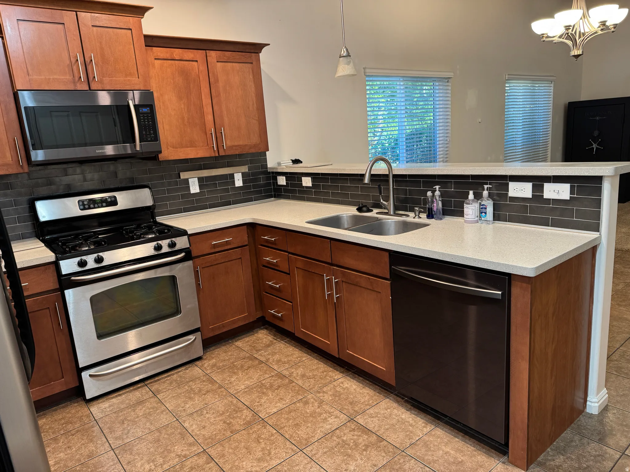 Kitchen featuring wood cabinetry, stainless steel appliances, a tile backsplash, and light-toned countertops