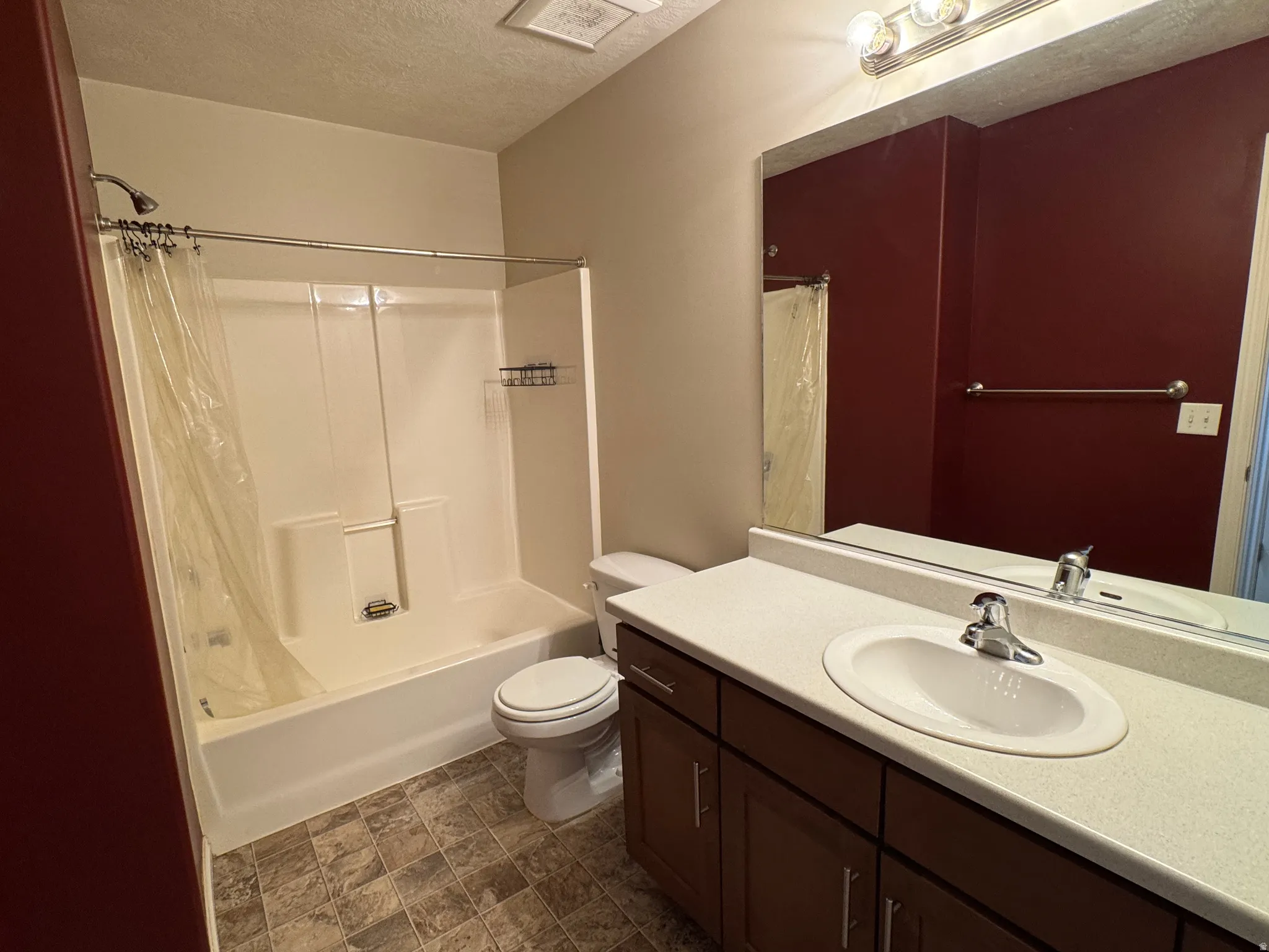 Spacious bathroom featuring a ceramic pedestal sink with chrome fixtures, wood-finish vanity cabinetry, large framed mirror, and an enclosed shower-tub combination with tile surround and curved shower rod