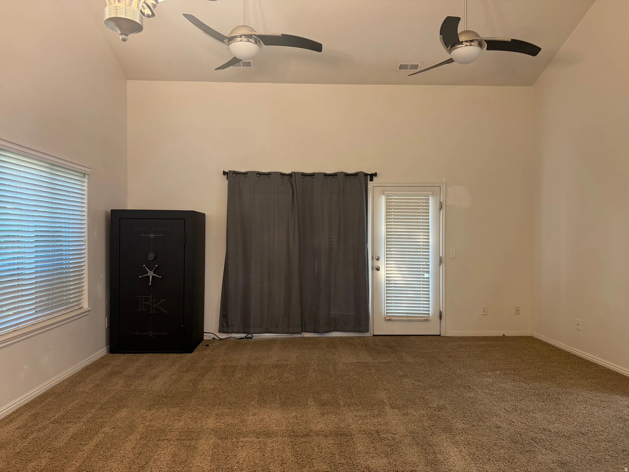 Spacious room featuring neutral wall finishes, carpet flooring, and abundant natural light from multiple windows