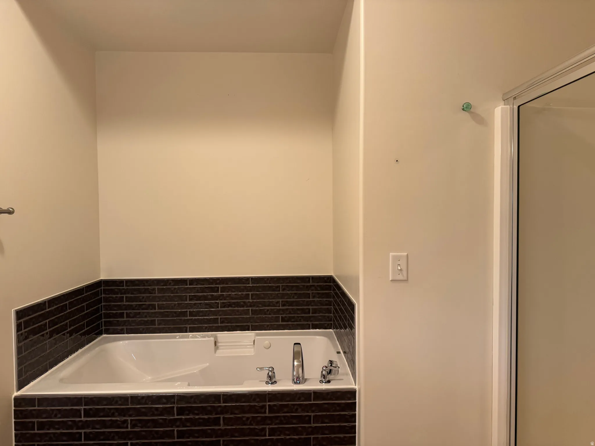Soaking tub surrounded by dark subway tile