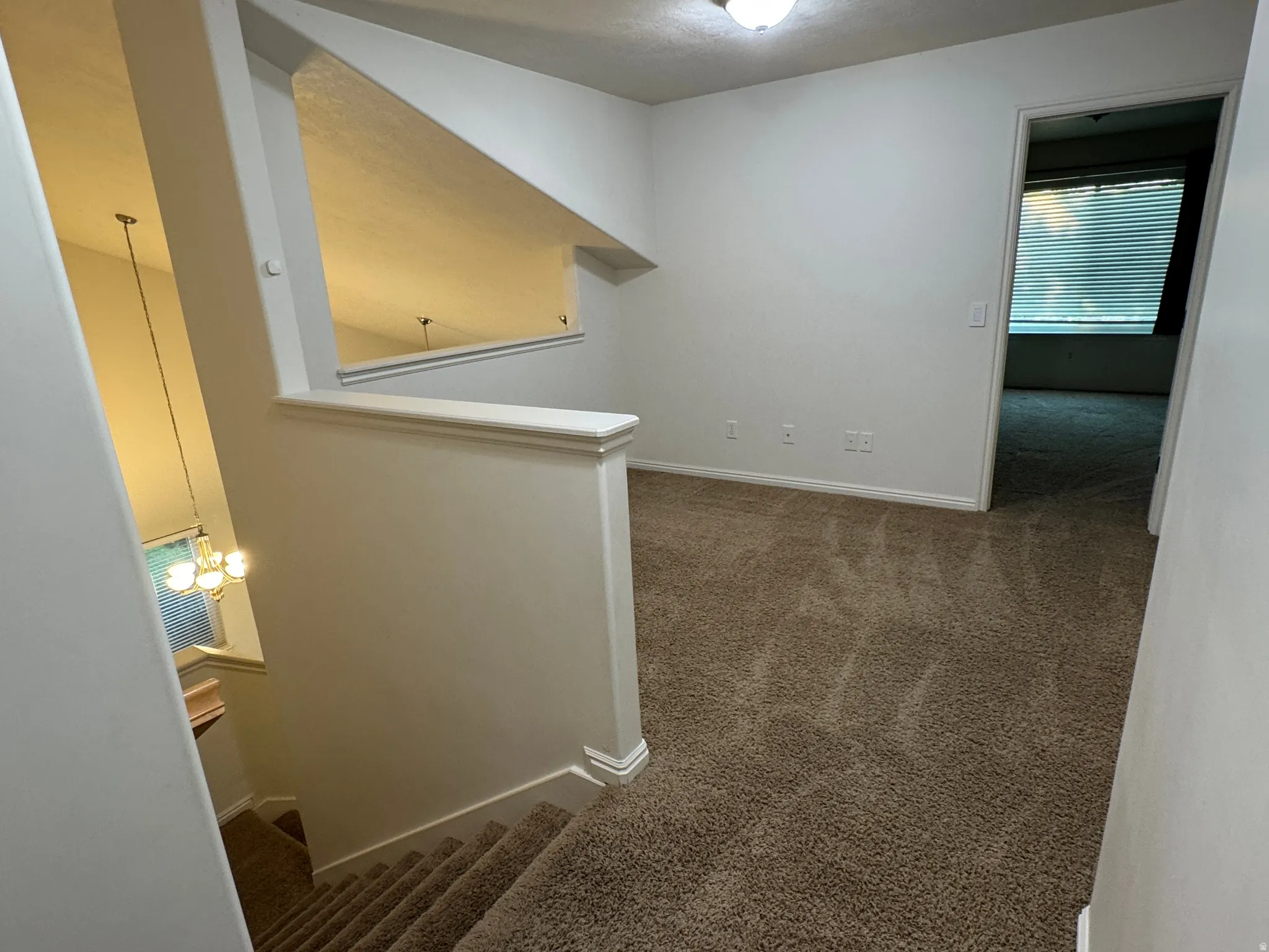 Open floor plan showcasing neutral carpeting, white trim detailing, and recessed lighting throughout