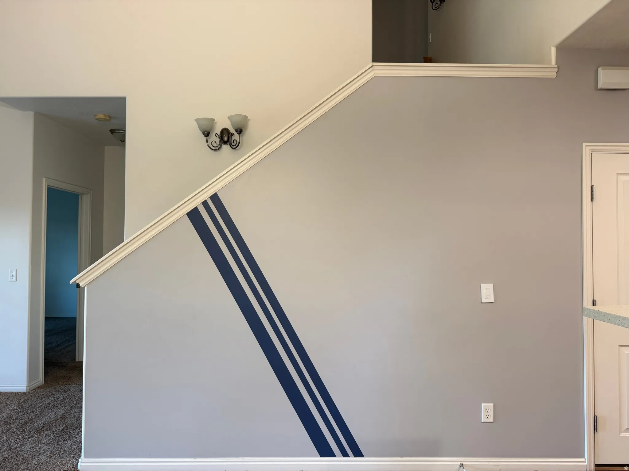 Staircase featuring a white handrail, decorative wall sconce, and a contrasting blue stripe accent wall