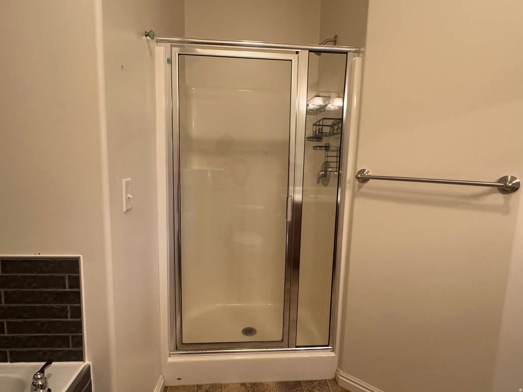 Enclosed shower with a chrome-framed glass door, integrated shelving, and a coordinating polished chrome towel bar