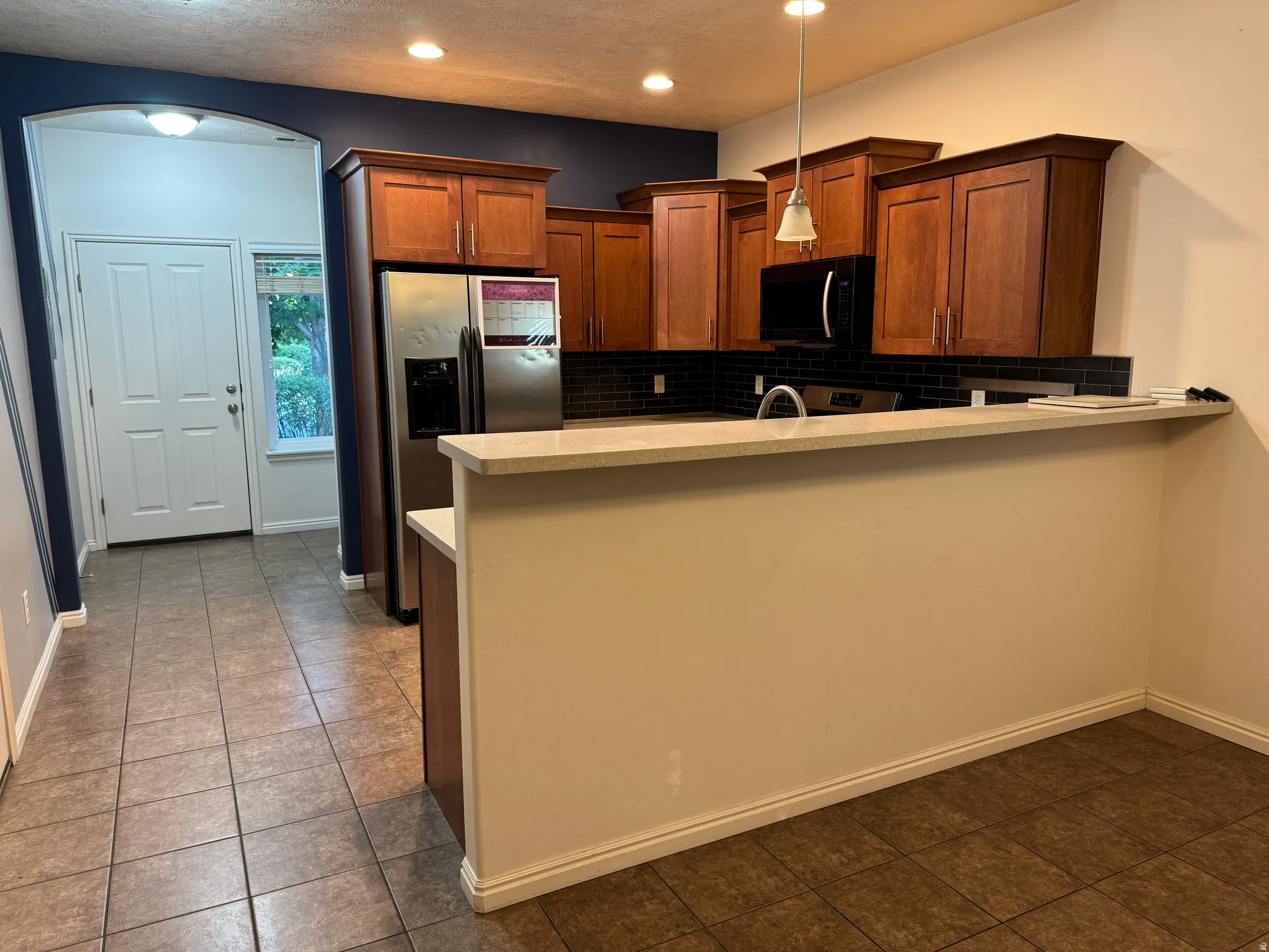 Kitchen featuring wood-finish cabinetry, stainless steel appliances, and a light-toned countertop