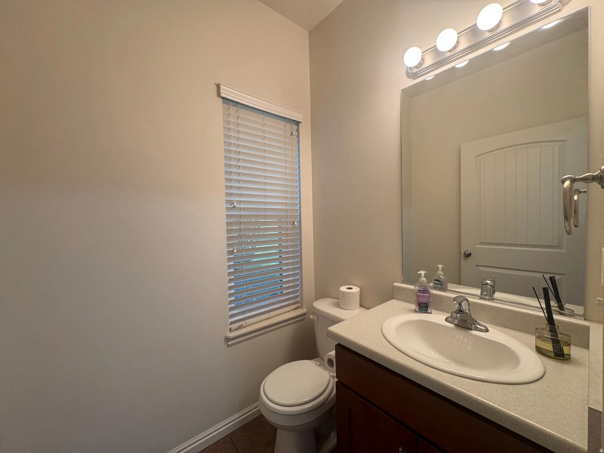 Bathroom featuring a wood-finish vanity with a light-colored countertop and an undermount sink
