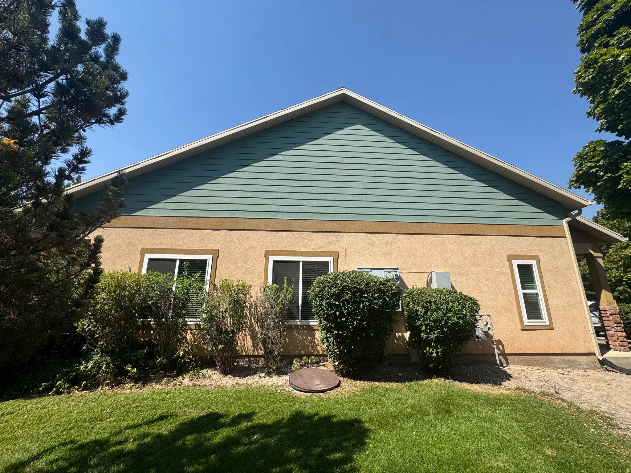 Two-tone exterior with horizontal siding and stucco finish, featuring white-framed windows and a well-maintained lawn