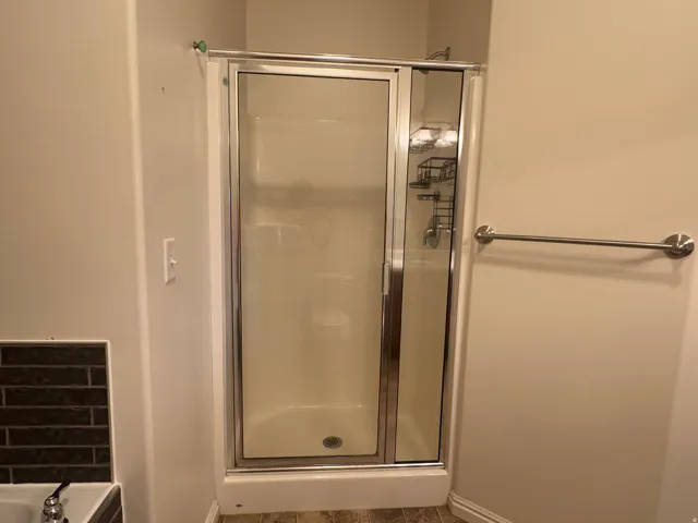 Enclosed shower with a chrome-framed glass door, integrated shelving, and a coordinating polished chrome towel bar