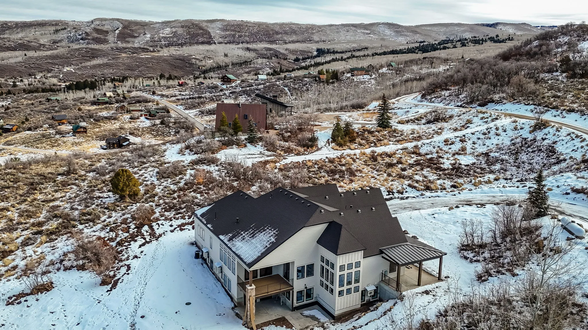 Drone photo showing front porch, impressive stairwell, deck and patios during construction phase