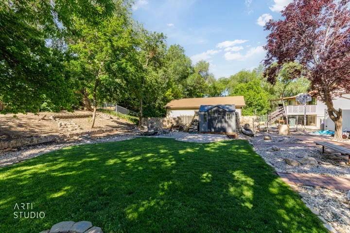 Expansive backyard featuring a lush lawn, established trees, and a detached shed