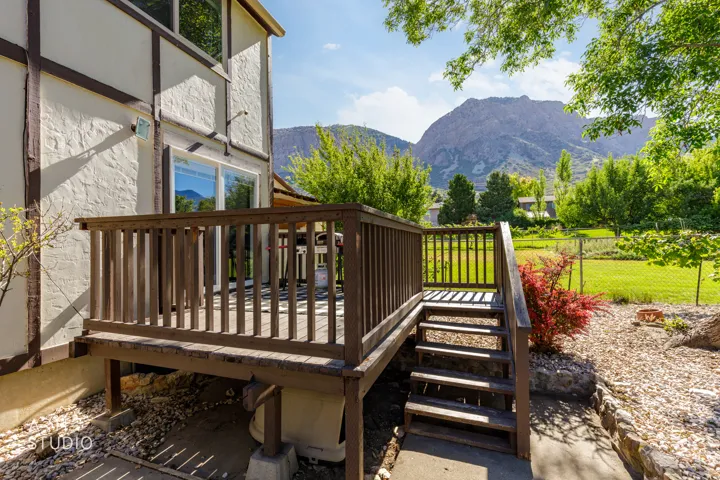 Spacious wooden deck with steps descending to a landscaped area, featuring a sliding glass door entry to the home