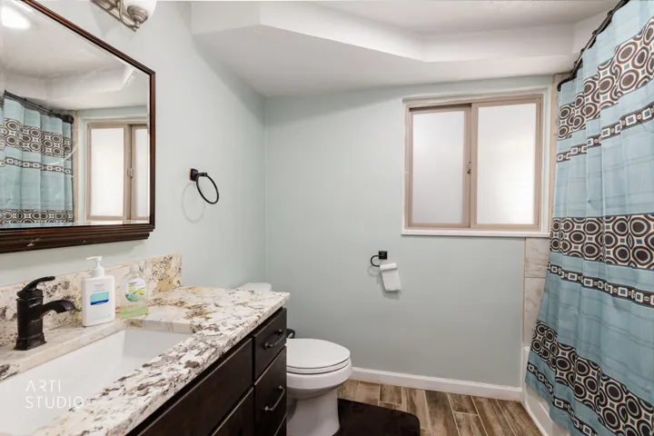 Updated Bathroom with Granite Countertops, Dark Cabinetry, and Decorative Tile AccentsThis bathroom features a spacious vanity with granite countertop and dark wood cabinetry offering ample storage