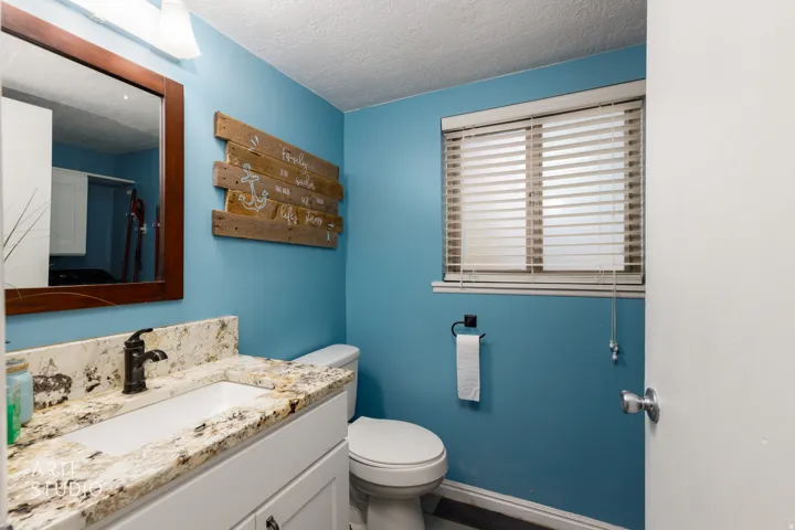 Vanity featuring a stone countertop with an integrated sink, dark bronze-finish faucet, and a framed mirror