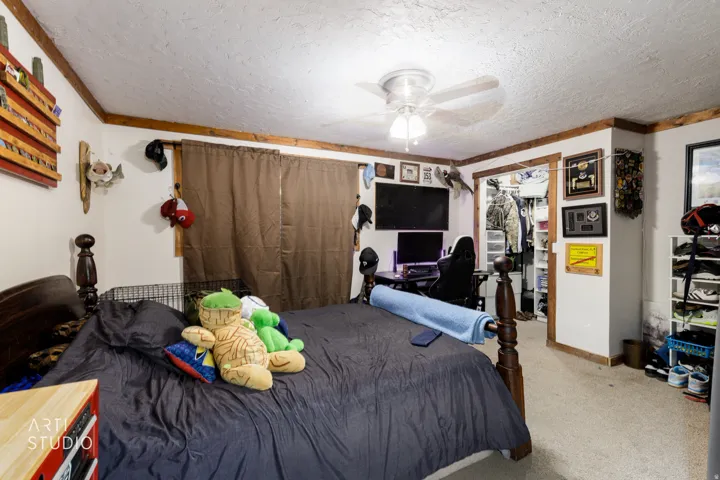 Carpeted interior room featuring a ceiling fan with integrated lighting, wood-finish trim, and a built-in closet with bifold doors