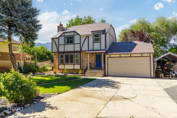 Tudor-style colonial featuring a striking black and white exterior with stone accents, arched entryway, and professional landscaping
