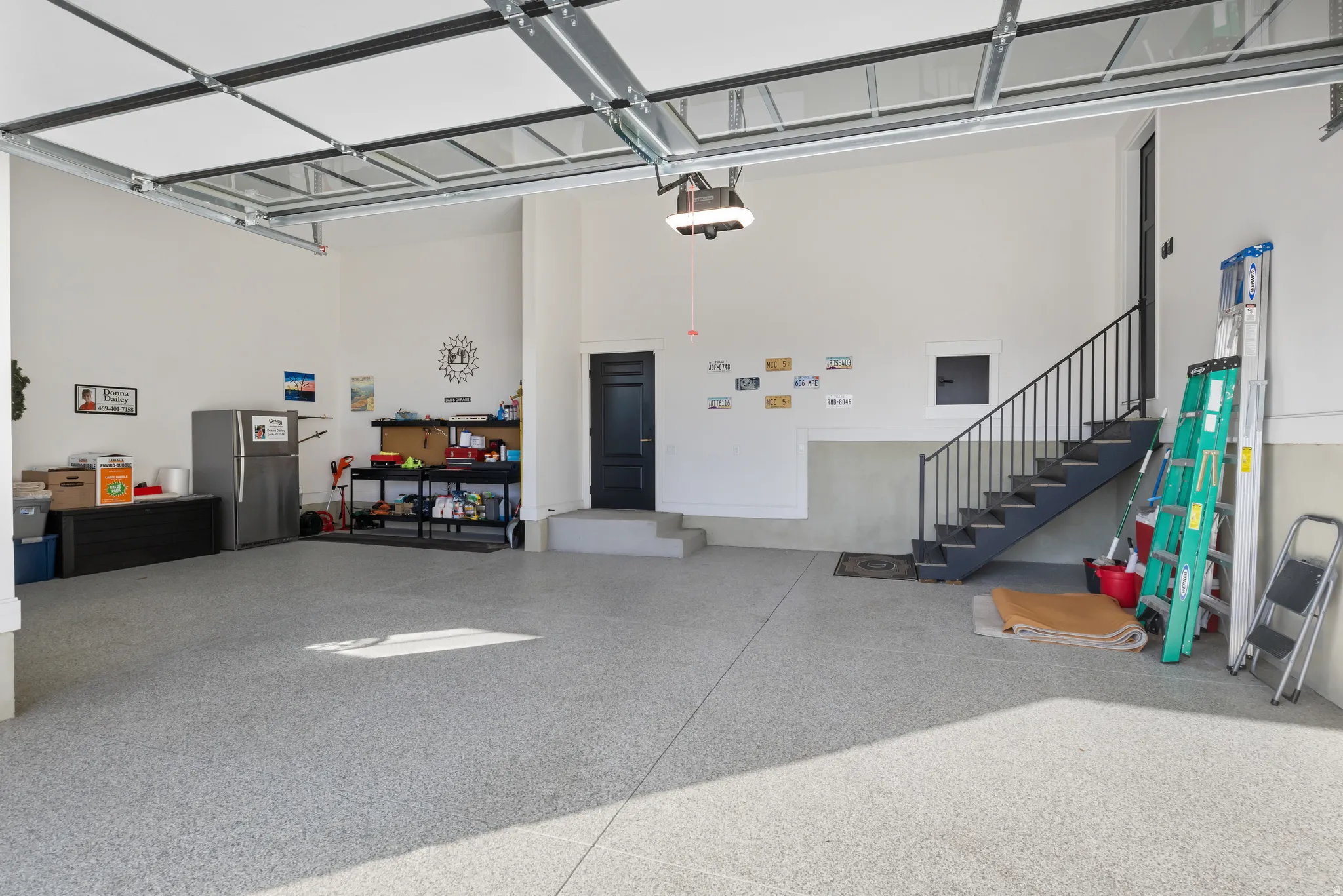 Spacious garage featuring a durable epoxy-coated floor, automatic overhead door, and direct access door