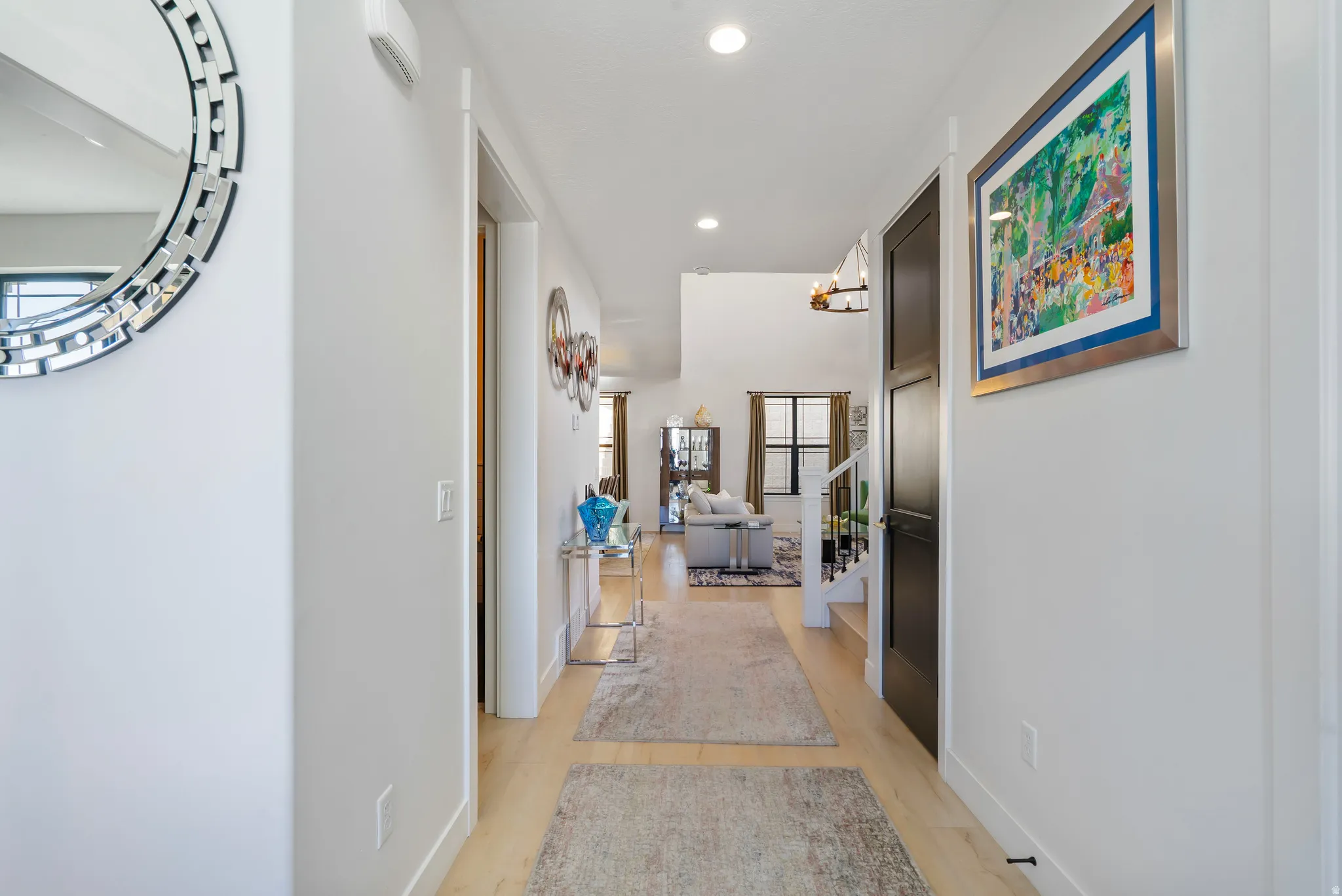 Long hallway with light wood-finish flooring, white walls, and recessed lighting