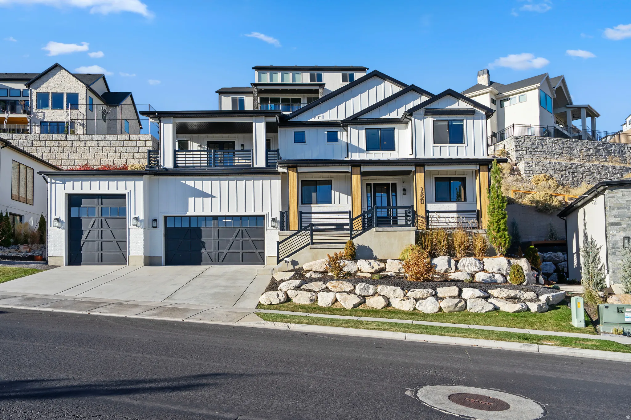 Modern farmhouse-style exterior featuring white vertical siding, black trim accents, and a dual two-car garage